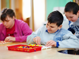 Photo of three children playing together at a table.