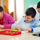 Photo of three children playing together at a table.